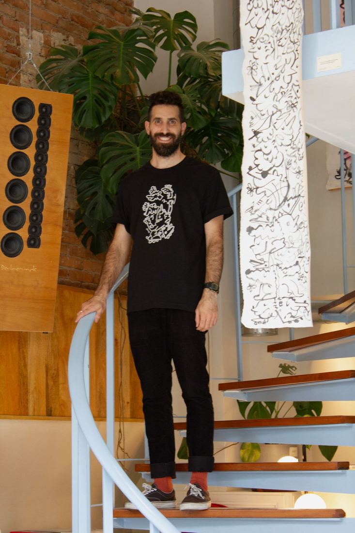 Shacyz standing beside a long hand-drawn artwork
